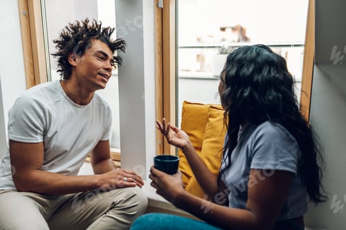 Two friends sharing a warm, open conversation by a sunny window