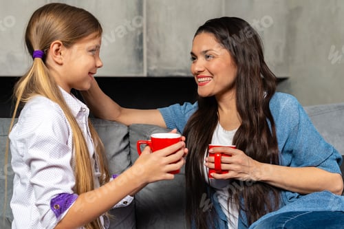 A mother and daughter smiling over warm drinks